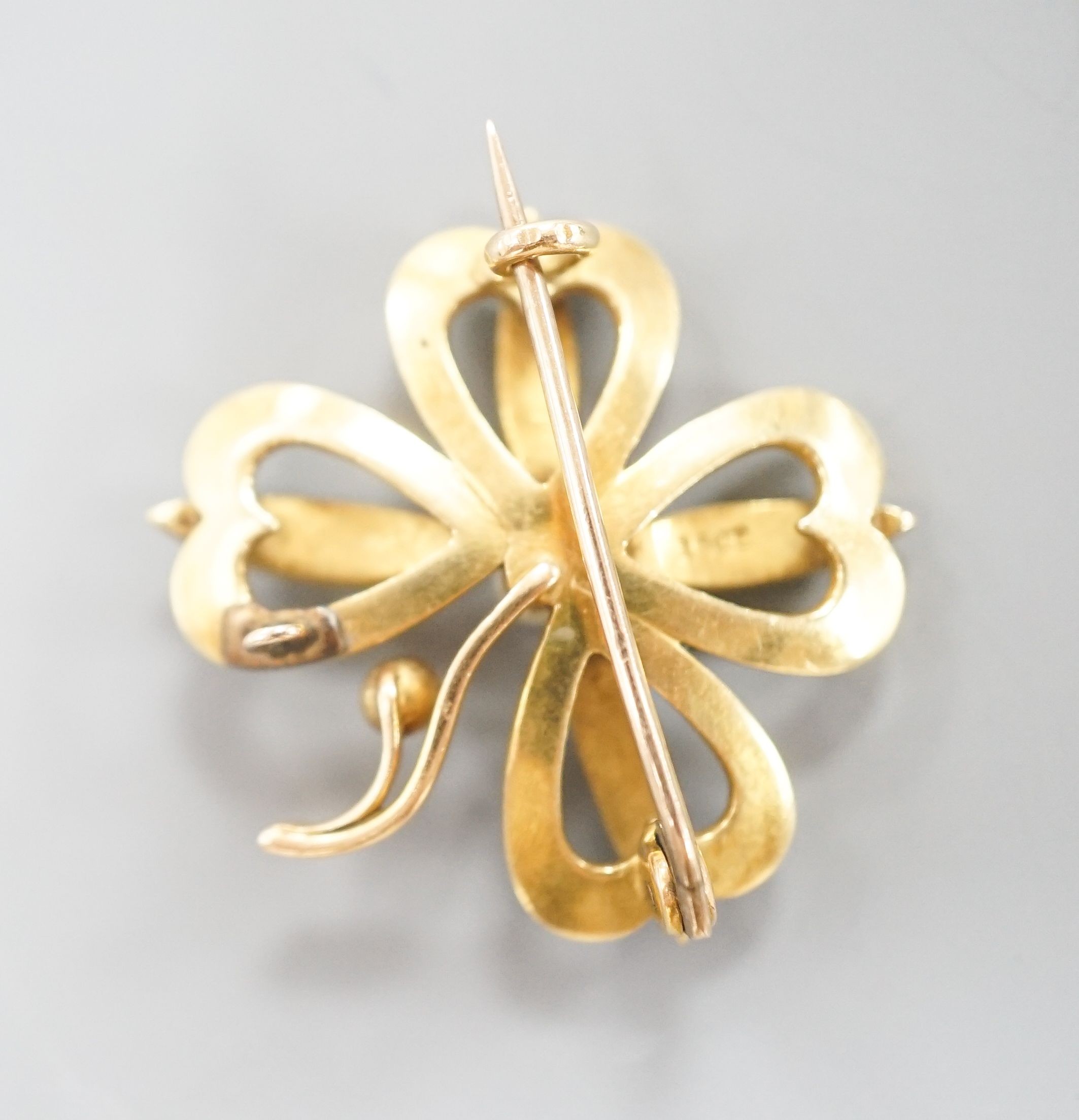 An Edwardian 15ct, seed pearl and green enamel set clover brooch, with later bale attachment, width 24mm, gross weight 4.4 grams.